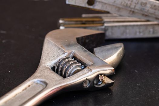 Tools for repair and building. Adjustable spanner, ruler and instruments on black wooden table with copy space