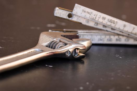 Tools for repair and building. Adjustable spanner, ruler and instruments on black wooden table with copy space