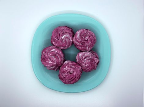 Bright appetizing raspberry marshmallow on a turquoise saucer.