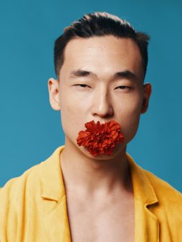 Korean male with narrow eyes yellow jacket and red flower in his mouth. High quality photo