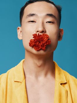 Sexy guy with a red flower in his mouth close-up portrait. High quality photo