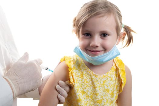 Doctor in a white coat is vaccinating a young Caucasian girl in yellow dress isolated on white background