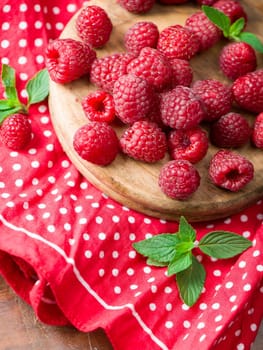 Ripe sweet raspberries in bowl on wooden table.