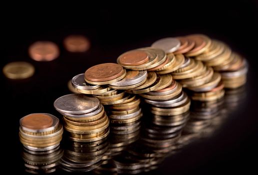 Stacks cf different country coins on black background.