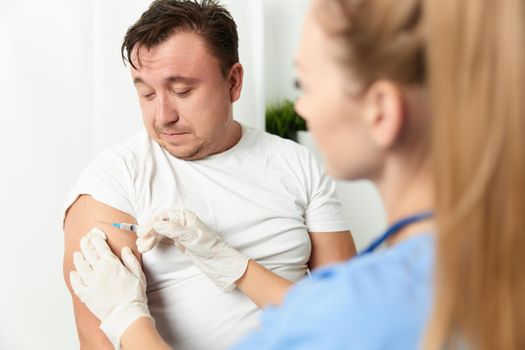 a woman doctor injects a vaccine into a man's hand close-up. High quality photo