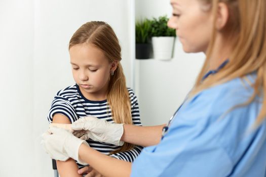 a woman doctor next to a girl seals her hand with a health adhesive. High quality photo