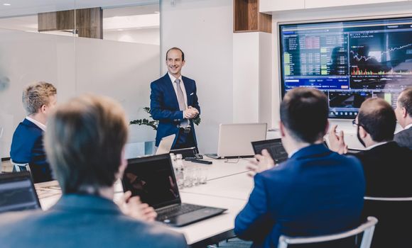 Business man making a presentation at office. Business executive delivering a presentation to his colleagues during meeting or in-house business training, explaining business plans to his employees.