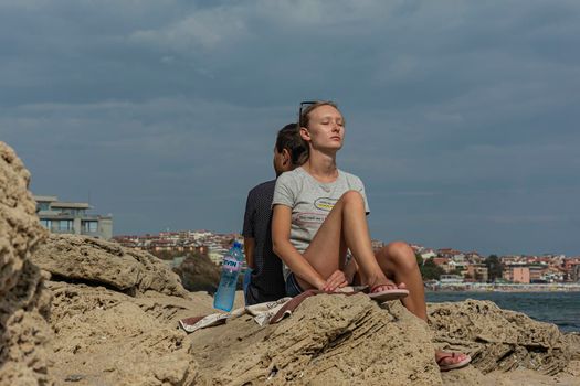 Bulgaria, Sozopol - 2018, 06 September: A girl sits with her back to a guy with her eyes closed, blurred background. Stock photo.