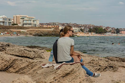 Bulgaria, Sozopol - 2018, 06 September: A girl with a guy sitting on the rocks near the sea, blurred background. Stock photo.