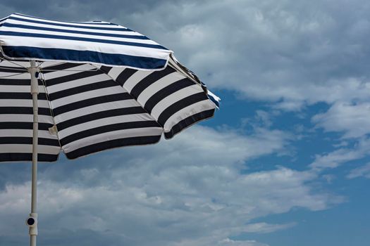 Beach umbrella from the sun on the background of blue sky with cirrus clouds. Stock photo.