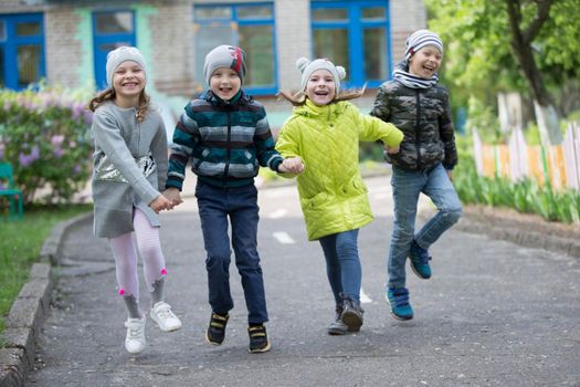 Belarus, the city of Gomel, May 10, 2019. Open day in kindergarten.Happy preschoolers on the street. Children holding hands jumping. A group of six year old friends.