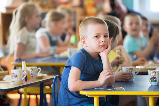 Belarus, the city of Gomil, April 25, 2019. Photoshoot in an institution. Children eat in kindergarten. Boy with a spoon at the table
