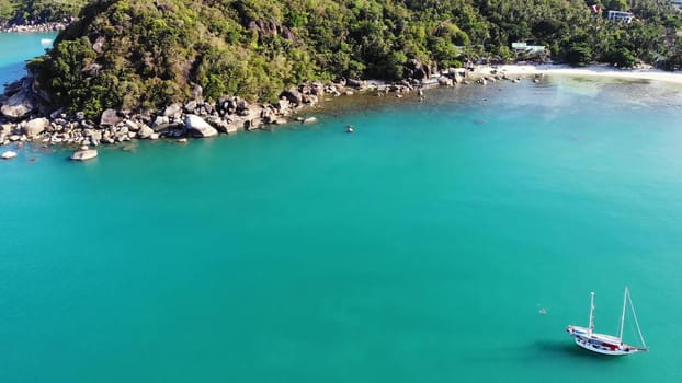 Boat near tropical shore. Amazing drone view of modern yacht sailing on calm sea water near coast of tropical volcanic island. Exotic Paradise Koh Samui, Silver Beach