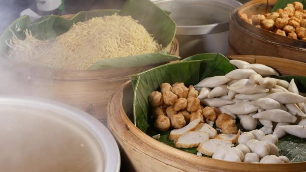 Bowls with various Asian dishes in diner. Wooden bowls with assorted traditional Thai dishes for sale placed on stall of street diner in city