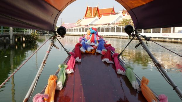 Tourist trip on Asian canal. View of calm channel and residential houses from decorated traditional Thai boat during tourist trip in Bangkok