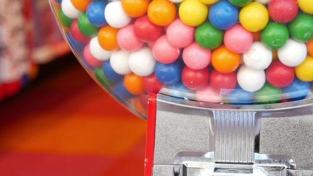 Colorful gumballs in classic vending machine, USA. Multi colored buble gums, coin operated retro dispenser. Chewing gum candies as symbol of childhood and summertime. Mixed sweets in vintage automate.