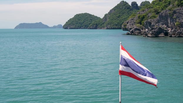 Group of Islands in ocean at Ang Thong National Marine Park. Archipelago in the Gulf of Thailand. Idyllic turquoise sea natural background with copy space. Waving flag as national symbol on the boat