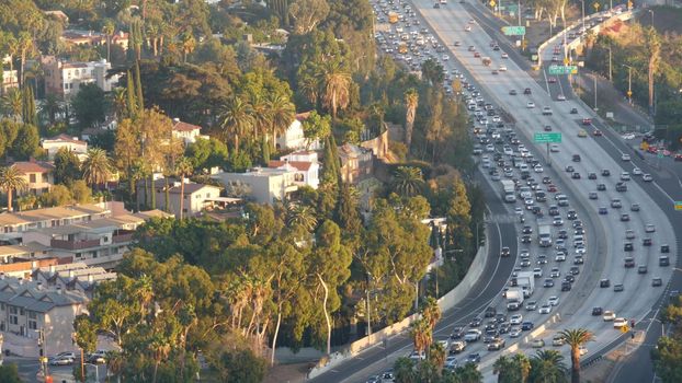 Busy rush hour intercity highway in metropolis, Los Angeles, California USA. Urban traffic jam on road in sunlight. Aerial view of cars on multiple lane driveway. Freeway with automobiles in LA city.