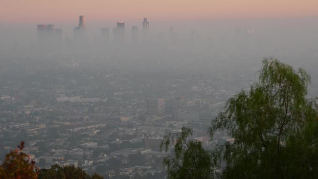 Highrise skyscrapers of metropolis in smog, Los Angeles, California USA. Air toxic pollution and misty urban downtown skyline. Cityscape in dirty fog. Low visibility in city with ecology problems.