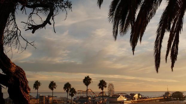 Classic ferris wheel, amusement park on pier in Santa Monica pacific ocean beach resort. Summertime California aesthetic, iconic view, symbol of Los Angeles, CA USA. Sunset golden sky and attractions.