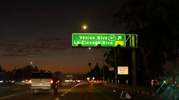 View from the car. Los Angeles busy freeway at night time. Massive Interstate Highway Road in California, USA. Auto driving fast on Expressway lanes. Traffic jam and urban transportation concept