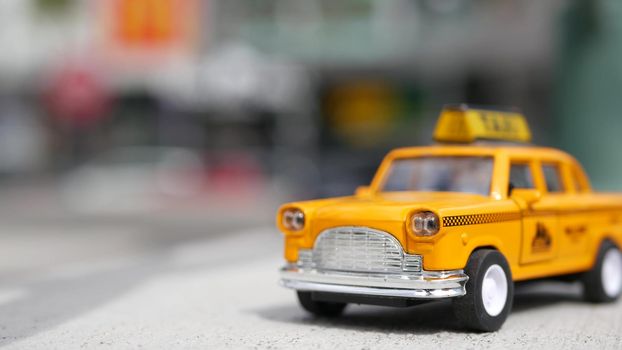 Yellow vacant mini taxi cab close up, Harmon corner, Las Vegas, USA. Small retro car model on defocused background. Little iconic auto toy as symbol of transport in soft focus. Blurred shopping mall.