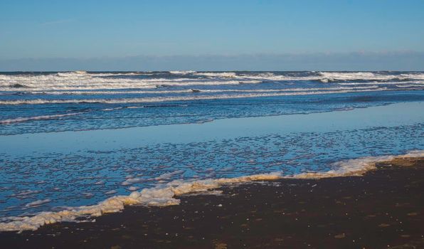 foam and waves form the north sea at the beach of hoek van holland in the netherlands