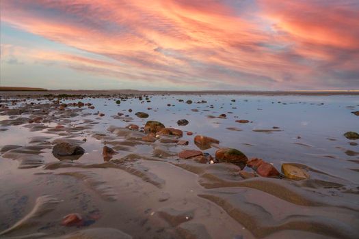 stones and water on the wet beach in Holland with cloudy sky as background