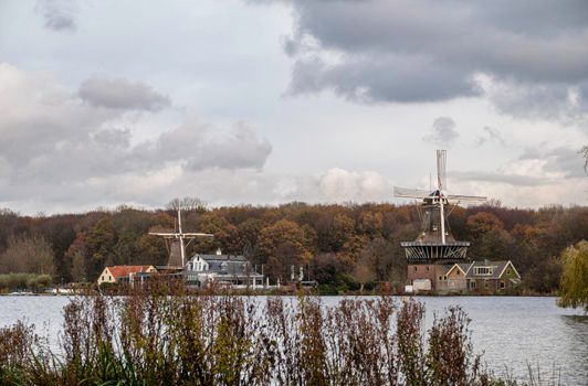 a pond in rotterdam park with two dutch windmills as background