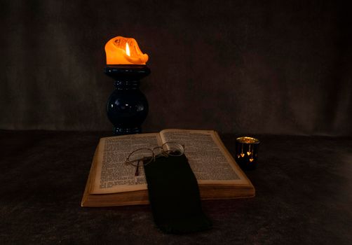 Burning candle and an open old Christian book still life