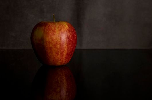 One red apple isolated on black acrylic sheet with reflection