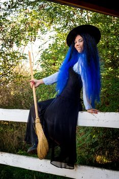 Halloween witch sitting on a fence with a broom