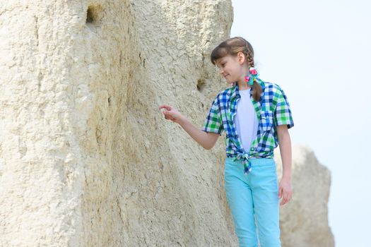 A ten-year-old girl picks a rock with her finger