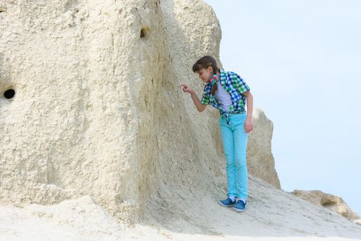 A girl of ten years old picks her finger in the rock with interest