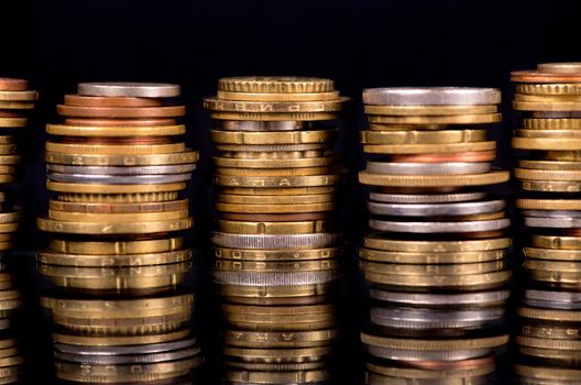 Stacks cf different country coins on black background.