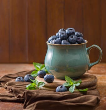 Fresh blueberry in a cup with leaves of mint.