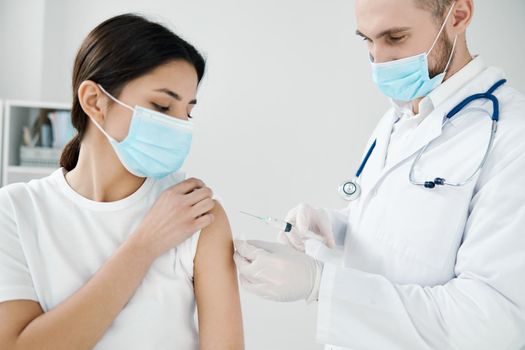 doctor in a medical gown and a woman in a protective mask covid-19 vaccination. High quality photo