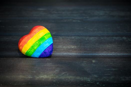 Heart with rainbow stripes on dark wooden background. LGBT pride flag, symbol of lesbian, gay, bisexual, transgender for social movements. Homosexual love,Equality or Human rights concept. Copy space.