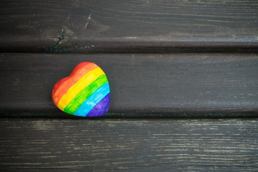 Heart with rainbow stripes on dark wooden background. LGBT pride flag, symbol of lesbian, gay, bisexual, transgender for social movements. Homosexual love,Equality or Human rights concept. Copy space.