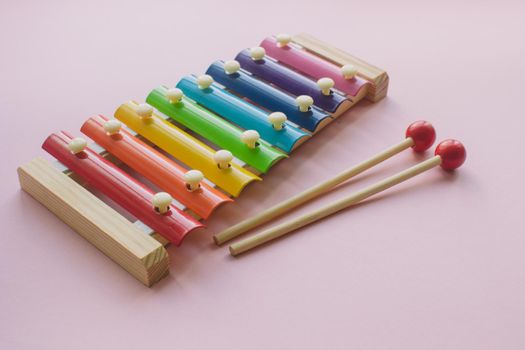 Rainbow Colored Wooden Toy Xylophone on pink bacground. Glockenspiel toy made of metal and wood