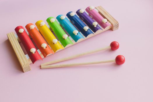 Rainbow Colored Wooden Toy Xylophone on pink bacground. Glockenspiel toy made of metal and wood