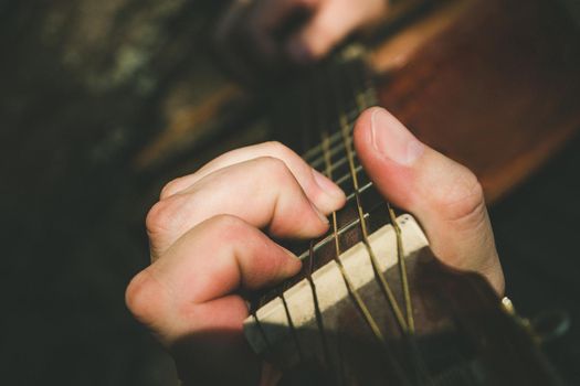 Fingers forming a chord on a guitar fingerboard. Male hand playing on guitar. Selective focus. Close up