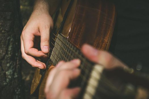 Fingers forming a chord on a guitar fingerboard. Male hands playing on guitar. Selective focus. Close up