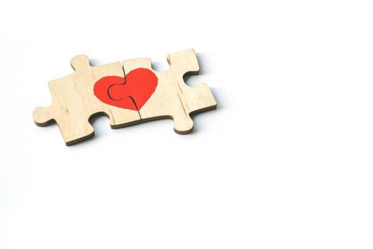 Red heart is drawn on the pieces of the wooden puzzle lying next to each other isolated on white background. Love concept. St. Valentine day. Copyspace.