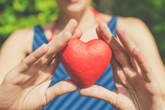 people, relationship and love concept - womans hands holding red heart on blue background