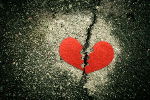 divorce concept - broken red heart on cracked asphalt