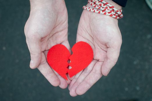 Broken heart in male hands - divorce concept. Top view