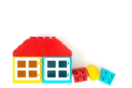 Colorful House made of Small and big plastic constructor bricks on white background. Popular toys.