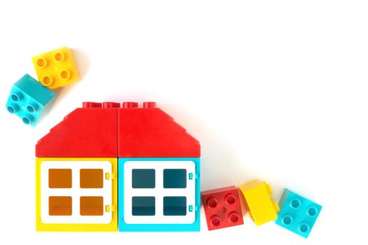 Colorful House made of Small and big plastic constructor bricks on white background. Popular toys.
