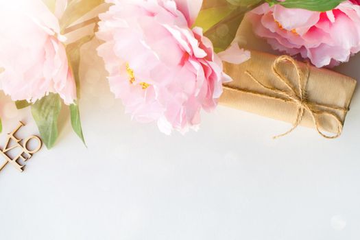 Bouquet of flowers and gift box wrapped with craft paper on white background with copy space for text. Greeting concept. Flat lay. Top view